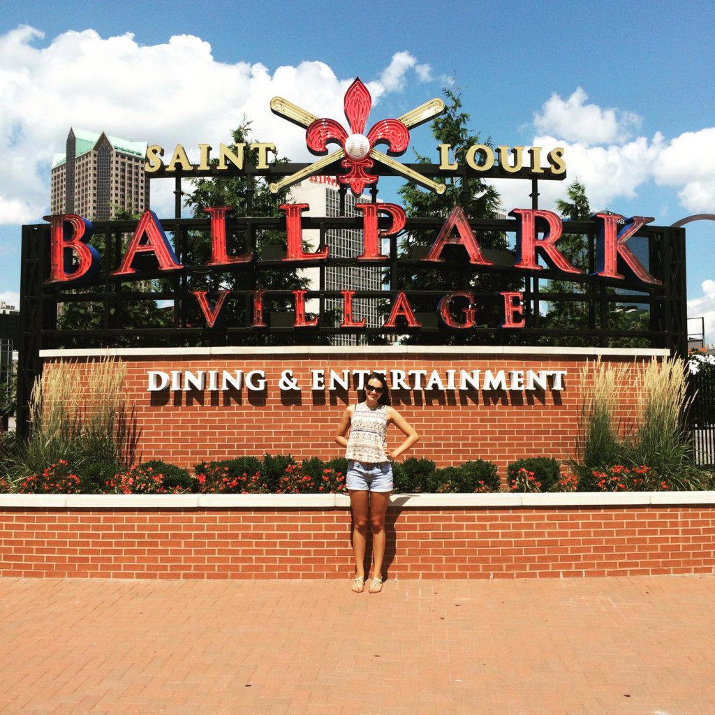 nicola standing in front of the ballpark village sign