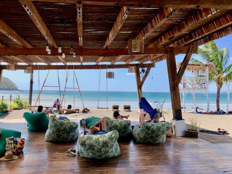 Hotel Selina Playa Venao relaxation deck, people read books in bean bag chairs while looking out over the sea